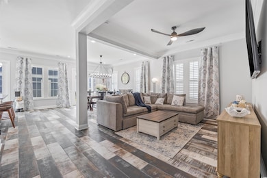 Living area with ceiling fan, a chandelier, crown molding, wood finished floors, and recessed lighting