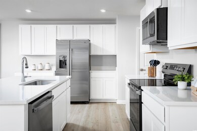 Kitchen featuring appliances with stainless steel finishes, light wood-style floors, white cabinets, light stone countertops, and recessed lighting