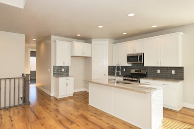 Kitchen with light stone counters, stainless steel appliances, white cabinets, tasteful backsplash, and recessed lighting