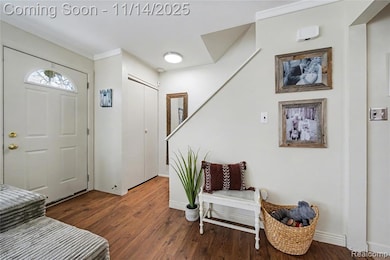 Entrance foyer with dark wood-style flooring, ornamental molding, and stairs