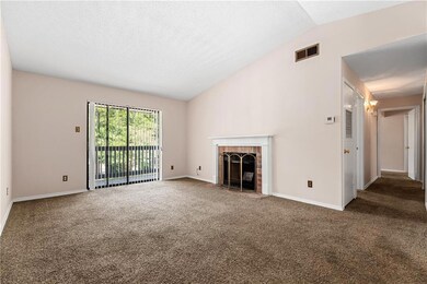 Unfurnished living room featuring vaulted ceiling, carpet, a brick fireplace, and a textured ceiling
