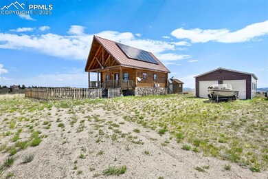 Back of property featuring a garage, a metal roof, roof mounted solar panels, an outbuilding, and a porch