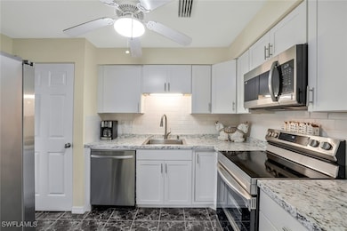 Kitchen featuring backsplash, stainless steel appliances, sink, and white cabinets