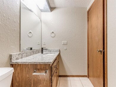 Bathroom with a textured wall, vanity, a textured 