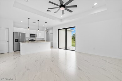 Unfurnished living room featuring a tray ceiling, light marble finish flooring, recessed lighting, and a ceiling fan