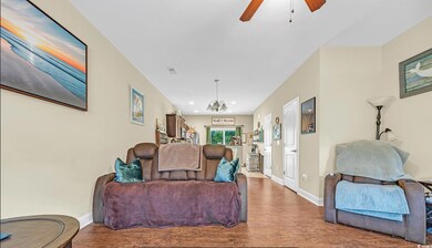 Living area featuring wood finished floors, baseboards, ceiling fan, and a chandelier