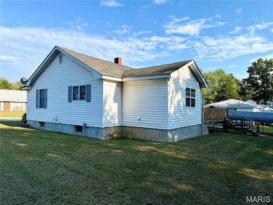 View of property exterior featuring a chimney, a lawn, and a deck