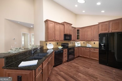 View of Kitchen from entry area.  Beautiful stained cabinets, gorgeous hardwood flooring, and peninsula that is perfect for a breakfast bar.  Sun tunnel for natural daylight.