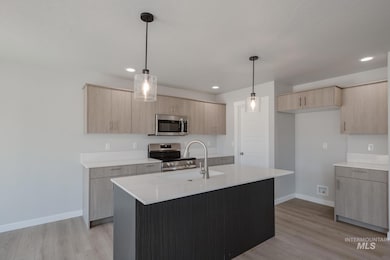 Kitchen with light brown cabinetry, appliances with stainless steel finishes, light wood-type flooring, and recessed lighting