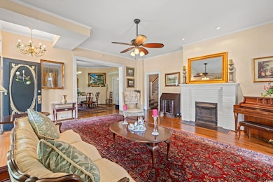 Living area with a ceiling fan, stairway, a chandelier, wood finished floors, and ornamental molding
