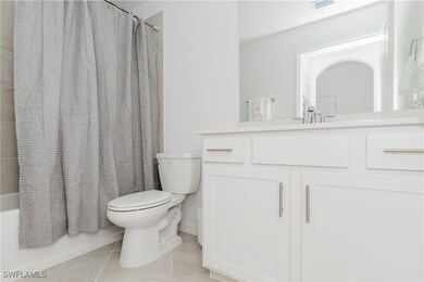 Full bath with shower / bath combo with shower curtain, light tile patterned floors, and vanity