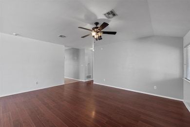 Spare room featuring dark wood-type flooring, vaulted ceiling, and ceiling fan