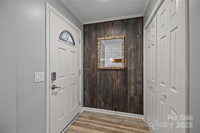 Foyer with updated front door, feature wall, wood-look flooring, crown molding, and convenient closet storage sets the tone for this fully renovated home.