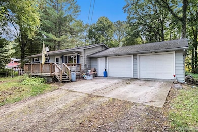 Ranch-style house with driveway, an attached garage, and a wooden deck