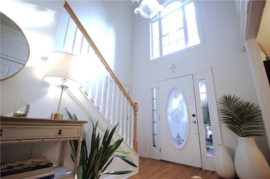 Foyer with a high ceiling, light wood finished floors, stairs, and a chandelier