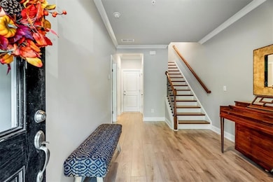 Entryway featuring light wood-style floors, crown molding, and stairs