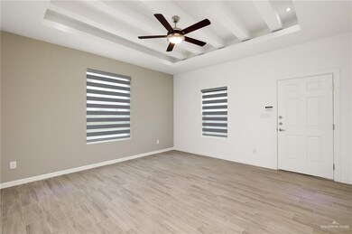 Empty room with beamed ceiling, light hardwood / wood-style flooring, a raised ceiling, and ceiling fan