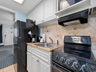 Kitchen with white cabinets, black appliances, lig