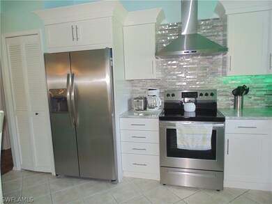 Kitchen featuring white cabinetry, wall chimney ra