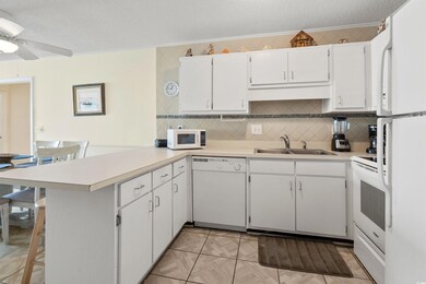 Kitchen with white appliances, a peninsula, a textured ceiling, crown molding, and light countertops
