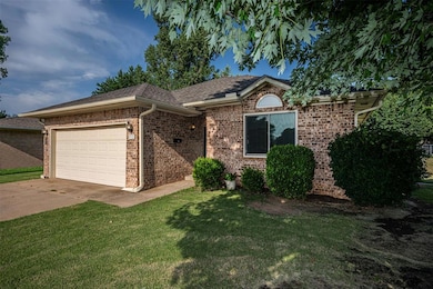 Ranch-style home with an attached garage, a front yard, concrete driveway, brick siding, and a shingled roof