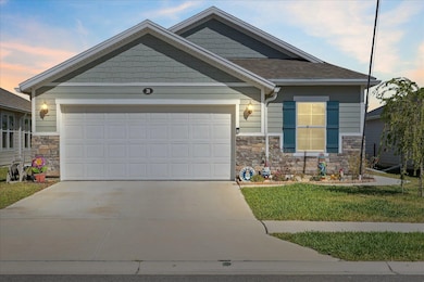Craftsman-style home featuring stone siding, concrete driveway, an attached garage, and a front lawn
