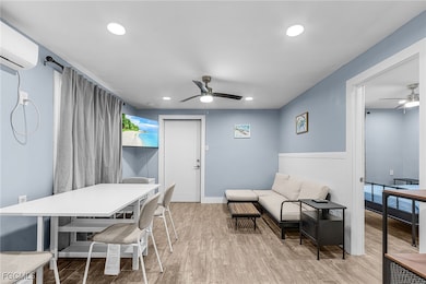 Dining space with a ceiling fan, light wood finished floors, recessed lighting, and an AC wall unit