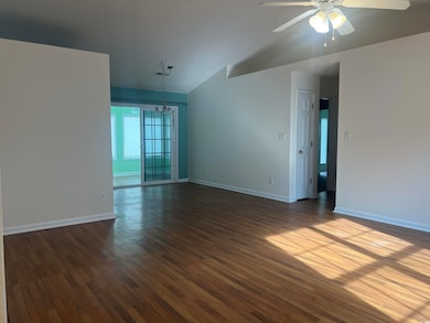 Spare room featuring dark wood-style flooring, ceiling fan, and vaulted ceiling