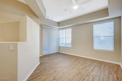 Empty room with ceiling fan, light wood-style flooring, and baseboards