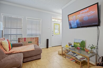 Living area featuring crown molding, light tile p