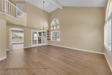 Unfurnished living room with a chandelier, light wood finished floors, beamed ceiling, high vaulted ceiling, and arched walkways