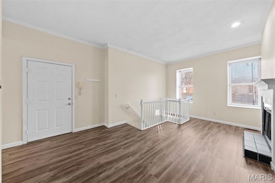 Unfurnished living room with crown molding, wood finished floors, and a fireplace