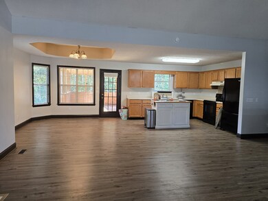 Large Kitchen with dining area off of main living room, Free standing island and Fridge to remain with Property. Exterior door leads to covered portion of oversized deck space.
