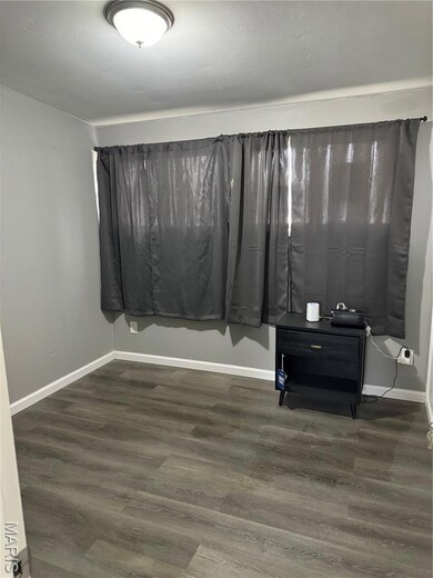 Empty room with dark wood-style flooring and baseboards