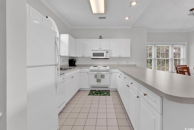 Kitchen with white appliances, a peninsula, a sink, light countertops, and recessed lighting