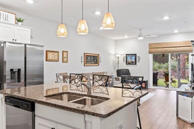 Kitchen featuring stainless steel appliances, open floor plan, a ceiling fan, a kitchen breakfast bar, and dark wood finished floors