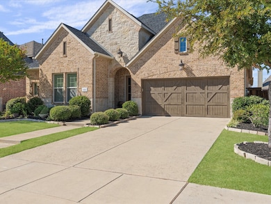 View of front of home featuring concrete driveway, brick siding, a garage, stone siding, and a front yard