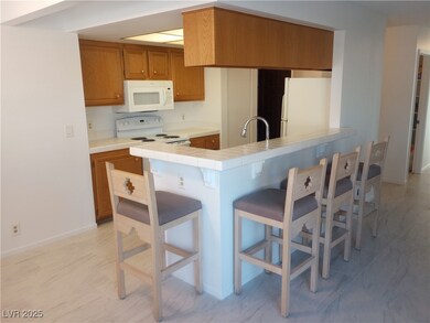 Kitchen featuring white appliances, a breakfast bar, brown cabinetry, and tile countertops