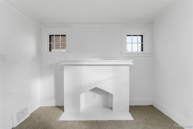 Detailed view of carpet flooring, a fireplace, and ornamental molding