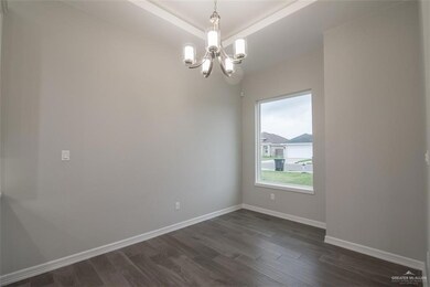 Empty room with dark wood-type flooring, an inviting chandelier, and a raised ceiling
