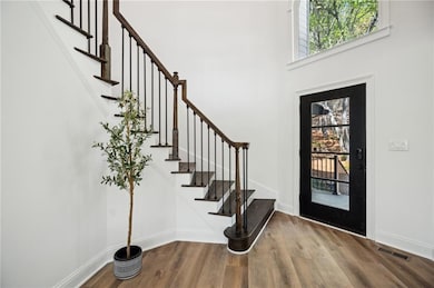 Foyer featuring stairway, visible vents, baseboards, and wood finished floors