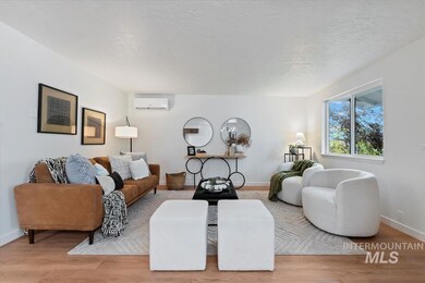 Living area featuring light wood-type flooring, a textured ceiling, and a wall mounted air conditioner