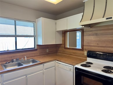 Kitchen featuring range hood, dishwasher, a sink,