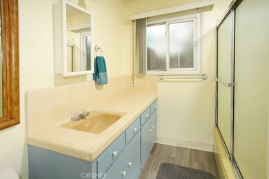 The guest bathroom includes glass enclosed shower, tile countered vanity, and easy care flooring.