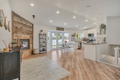 Kitchen featuring vaulted ceiling, white cabinets, a multi sided fireplace, light wood-type flooring, and tasteful backsplash