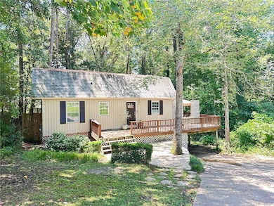 View of front of home featuring asphalt driveway, a wooden deck, a shingled roof, and a carport
