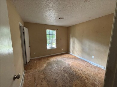 Unfurnished room with a textured ceiling and baseboards