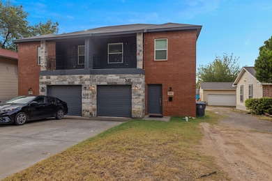 View of front facade featuring a balcony, brick siding, a front lawn, and driveway