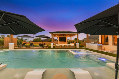 Picture yourself reclining on a beach lounger nestled in the refreshing pool waters, gazing towards the inviting pergola. It's a picturesque scene of relaxation and tranquility, where you can soak up the sun's warmth while enjoying the serene ambiance of your backyard oasis.