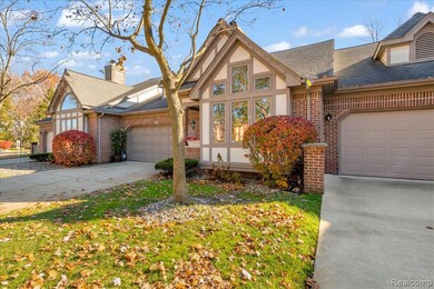 Tudor house featuring brick siding, a garage, driveway, and roof with shingles